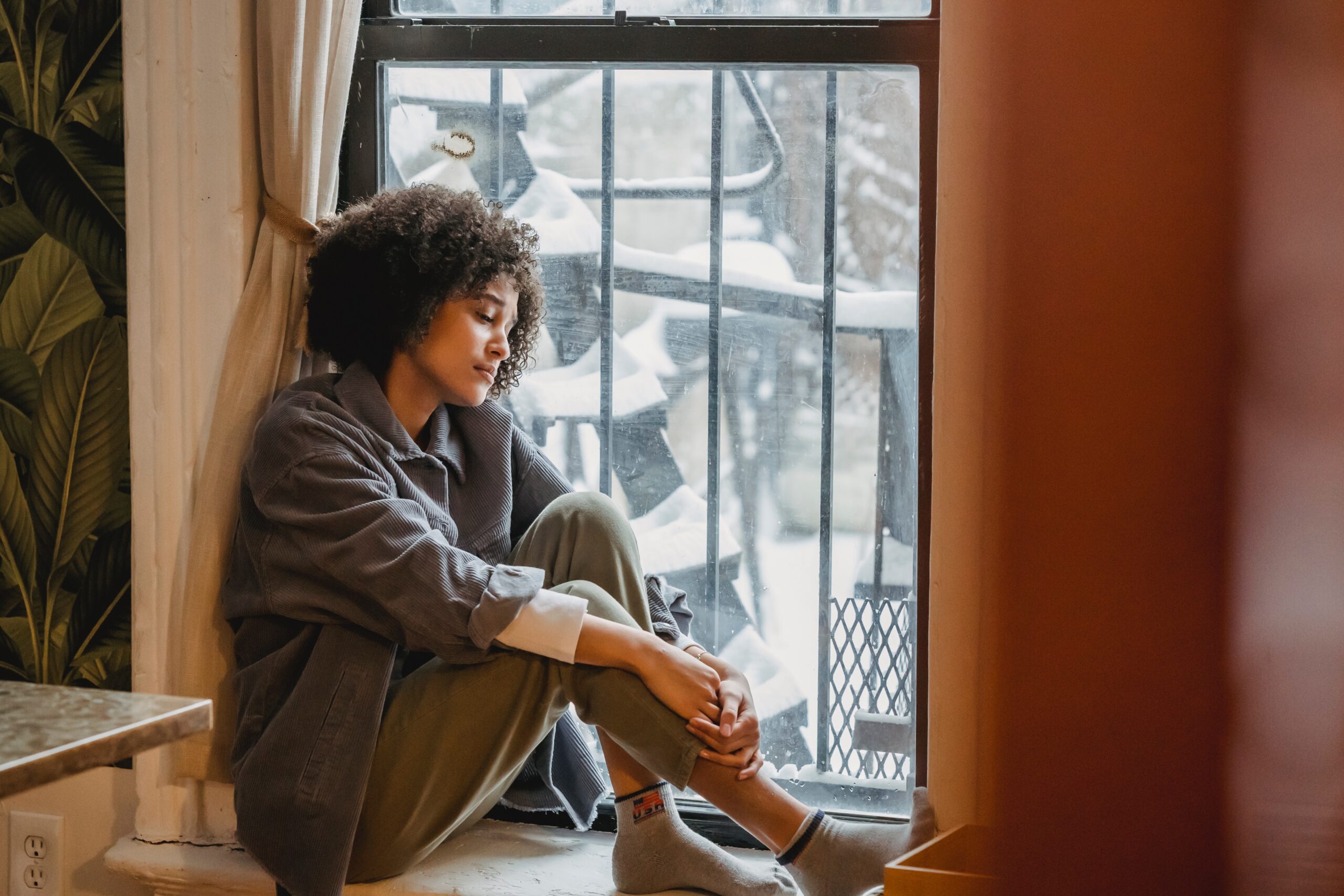 Sad woman in window seat for Understanding Genetic Predispositions to Depression post