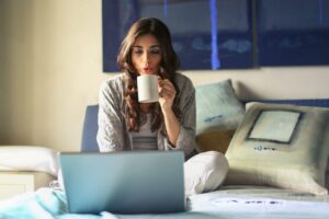 woman radimg a computer while drinking coffee enjoying her The Wellness Collective subscription