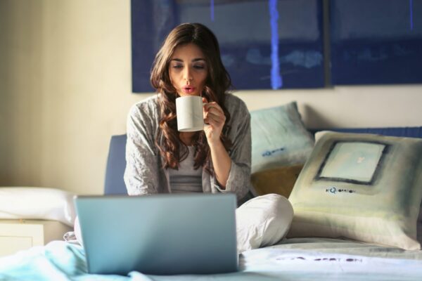 woman radimg a computer while drinking coffee enjoying her The Wellness Collective subscription